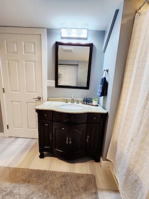 A bathroom with a vanity, sink, mirror, and shower curtain. - CozyCasita Modern Suit (Mission)