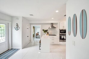 Een moderne keuken met witte kasten, een centraal eiland en een roestvrijstalen afzuigkap.