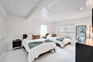 Une chambre moderne avec deux lits, une table de chevet, une commode et un grand miroir.