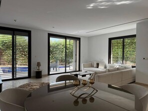 A modern living room with a dining area, large windows, and a view of the outdoors. - Malaga, duplex (Tunis)