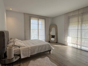 A bedroom with a bed, a chair, a round table, and large windows. - Malaga, duplex (Tunis)