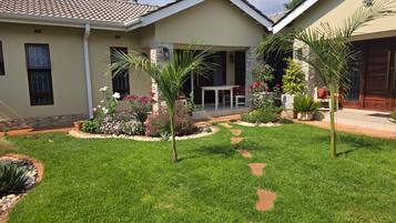 A residential property with a well-maintained lawn, a patio area with a table and chairs, and a variety of plants and flowers.