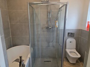 A bathroom with a glass-enclosed shower, a toilet, and a bathtub.