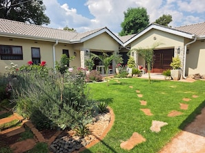 A residential property with a well-maintained lawn, a stone pathway, and a variety of plants.