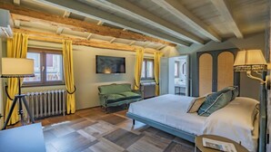 Un dormitorio con cama, escritorio, silla, radiador y ventana con cortinas.