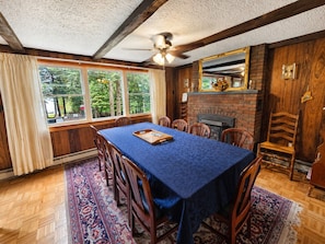 A dining room with a long table, chairs, a ceiling fan, and a brick fireplace. - Family Friendly getaway right across from community beach, pet-friendly with trail access (Beaver Cove)