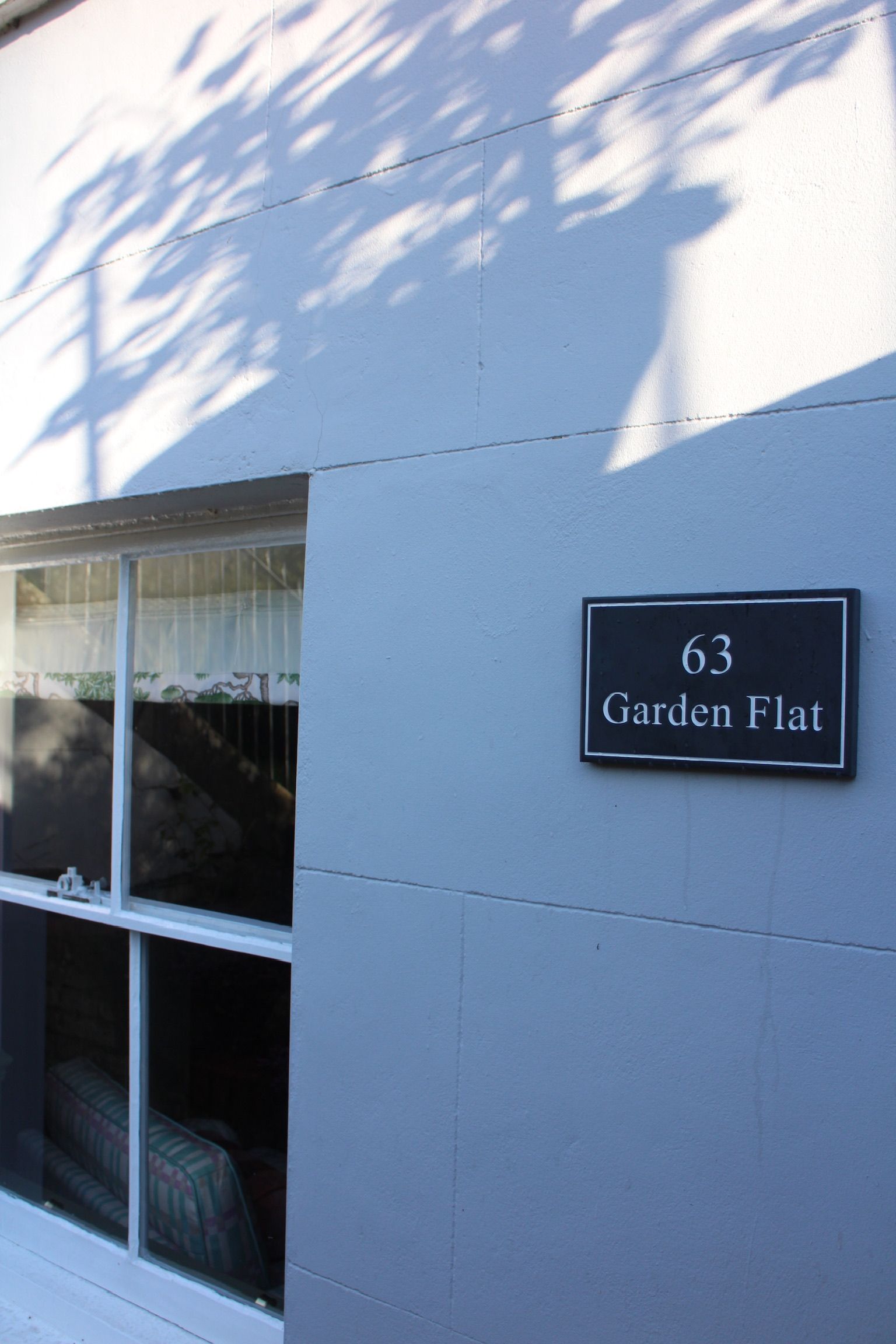 A house number sign '63 Garden Flat' mounted on a wall.