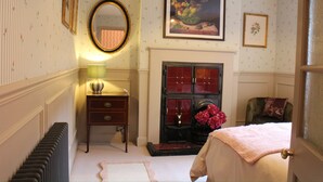 Ein Schlafzimmer mit Kamin, Spiegel, Schminktisch und Bett.