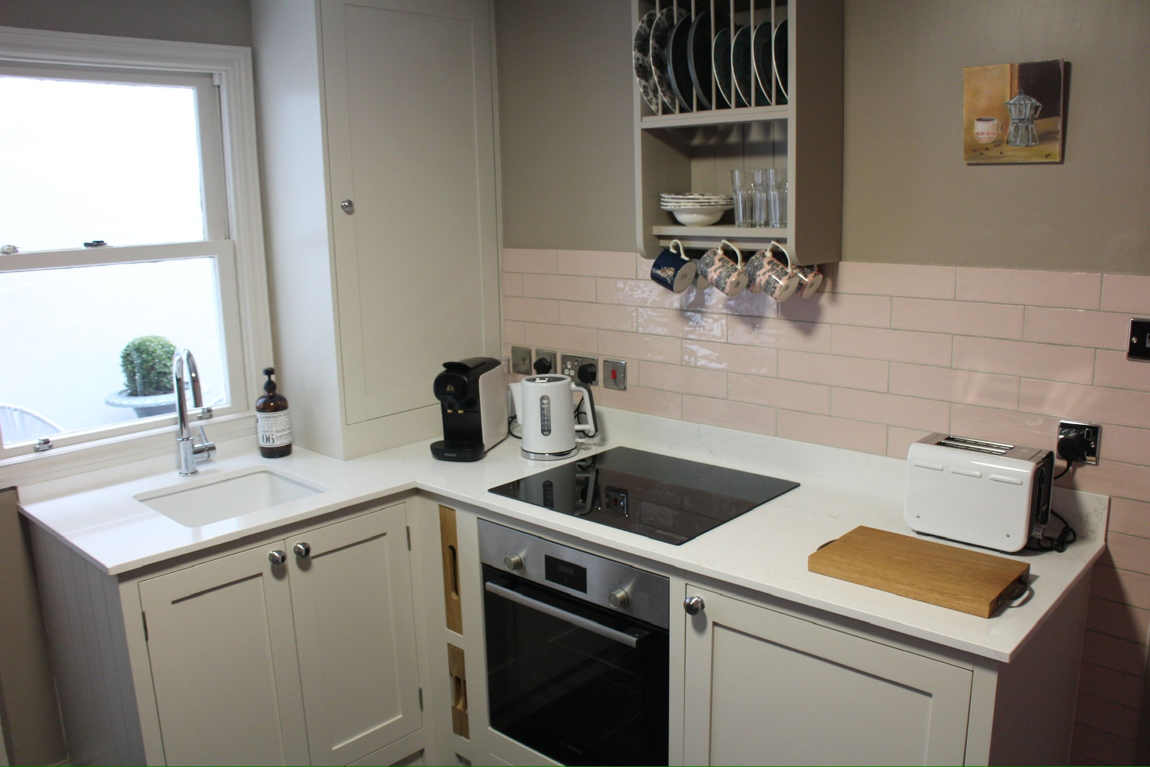 A modern kitchen with white cabinetry, a built-in oven, a toaster, and a coffee maker.