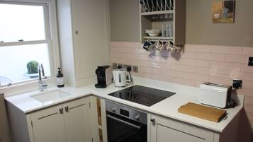 A modern kitchen with white cabinetry, a built-in oven, a toaster, and a coffee maker.