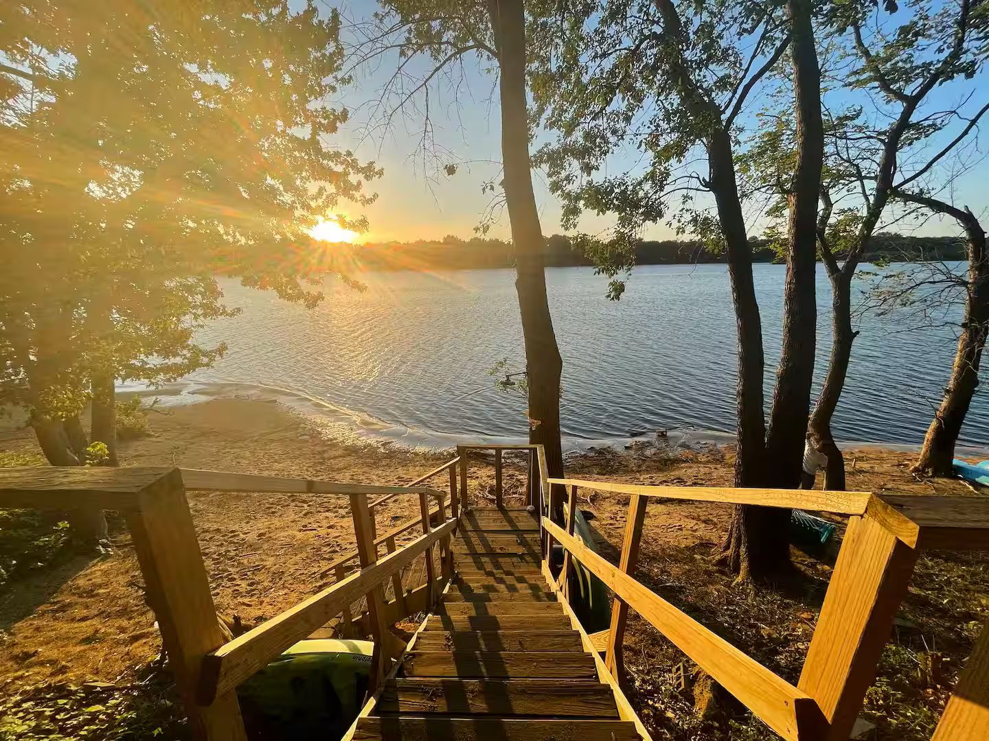 A wooden staircase leading to a dock over a calm lake, surrounded by trees.