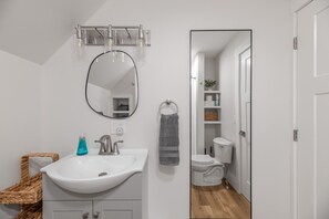Ein Badezimmer mit einem weißen Waschbecken, einem runden Spiegel und einer Toilette.