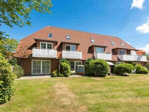 A two-story residential building with a red-tiled roof, multiple balconies, and a well-maintained lawn. - 10 in the Nis Randers House (St. Peter-Ording)