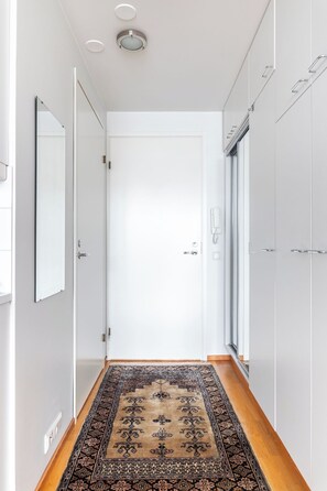 Un passadís amb una catifa amb dibuixos, portes blanques i un llum al sostre.