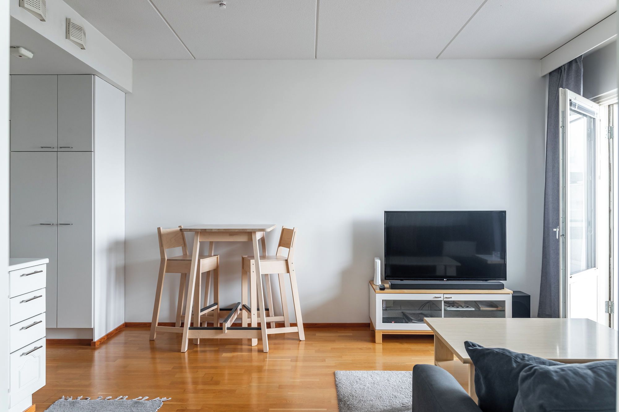 A modern living room with a TV, wooden furniture, and a view of the outdoors.