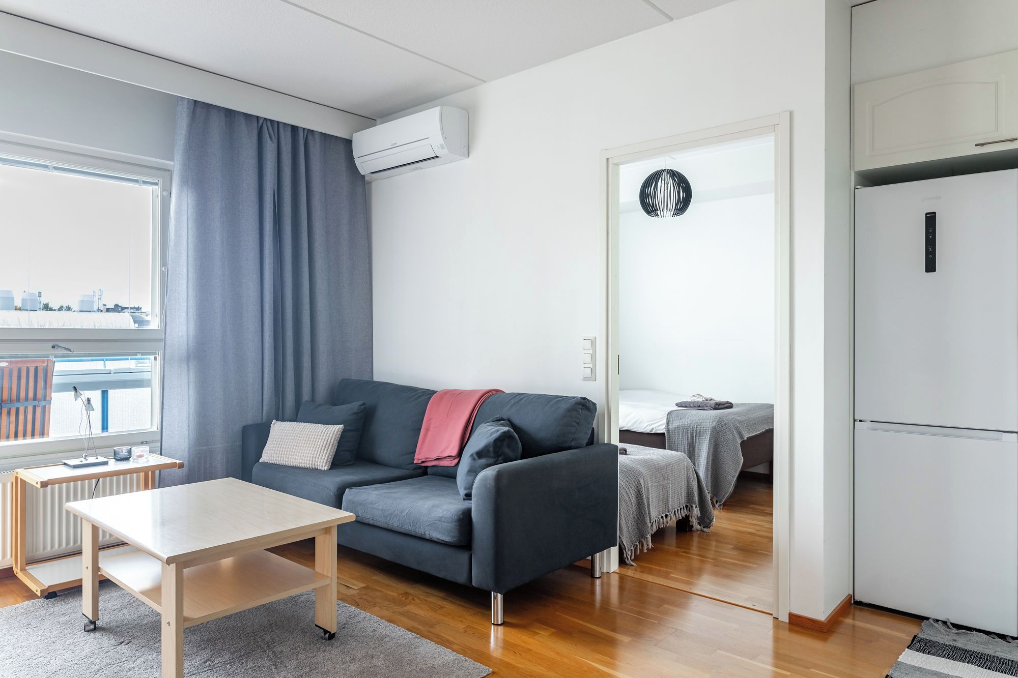 Una sala de estar moderna con un sofá, una mesita y vista a la ciudad a través de una ventana.