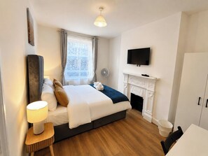 Ein Hotelzimmer mit Bett, Fernseher, Kamin und einem Vorhangfenster.