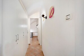 A hallway with white walls, a tiled floor, and a door leading to a kitchen area. - Enzo nel cuore di Napoli – Authentic Stay in Central Naples with Balcony (Napoli)