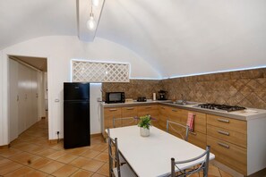 A compact kitchen with a refrigerator, microwave, stove, and a dining table with chairs. - Enzo nel cuore di Napoli – Authentic Stay in Central Naples with Balcony (Napoli)