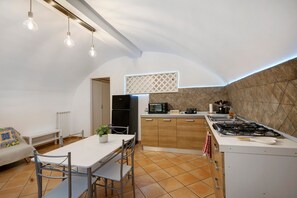 A compact kitchen with a dining area, a built-in oven, and a gas stove. - Enzo nel cuore di Napoli – Authentic Stay in Central Naples with Balcony (Napoli)