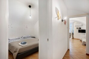 A bedroom with a bed, a bedside table, a wall-mounted light fixture, and a flat-screen TV. - Enzo nel cuore di Napoli – Authentic Stay in Central Naples with Balcony (Napoli)