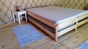 A wooden bed with a mattress and a small white nightstand with a lamp. - Őrálló Szer Jurtaszállás (Őriszentpéter)