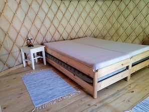 Ein hölzernes Bett mit einer Matratze und ein kleiner weißer Nachttisch mit einer Lampe.