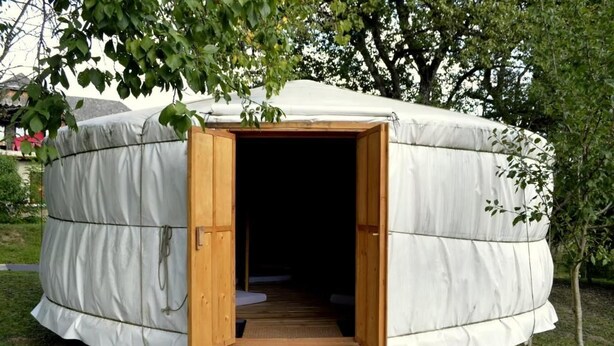 A round, covered structure with an open entrance and a wooden platform leading inside. - Őrálló Szer Jurtaszállás (Őriszentpéter)