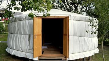 Estructura redonda cubierta con entrada abierta y una plataforma de madera que conduce al interior.