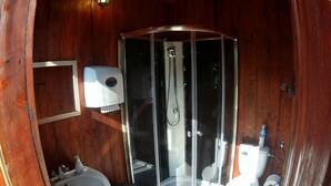A wooden cabin bathroom with a glass-enclosed shower, a sink, a toilet, and a soap dispenser. - Őrálló Szer Jurtaszállás (Őriszentpéter)
