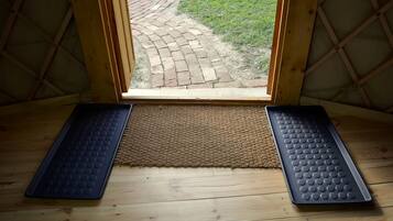 Una habitación con piso de madera, un felpudo y vista a un sendero de ladrillo que conduce al exterior.