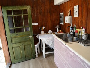Eine rustikale Küche mit Holztür, Spüle und verschiedenen Küchenutensilien.