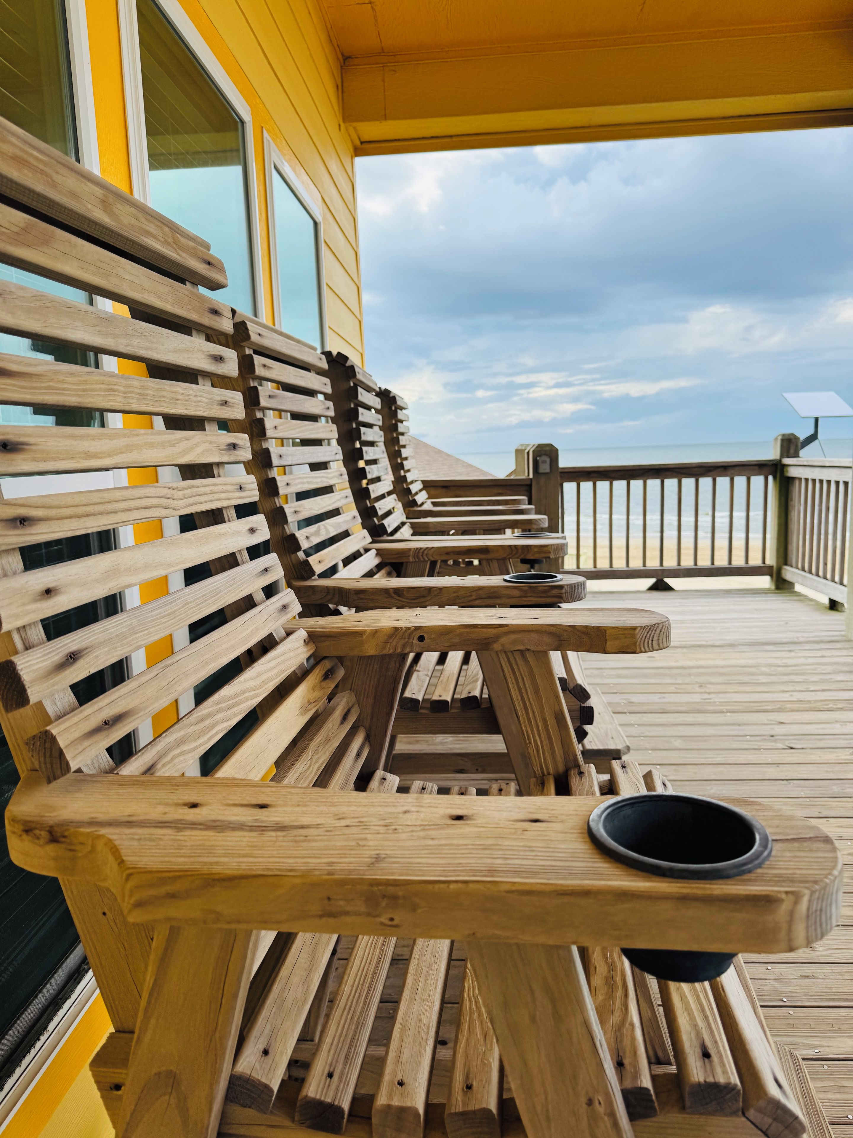 A wooden deck with benches and tables, overlooking a beach.