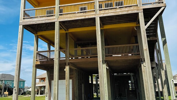 Un edificio de varios pisos con estructura de madera, un nivel superior cubierto y una entrada a nivel de calle.