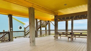 Una terraza de madera con techo amarillo, barandillas de madera y vista al mar.
