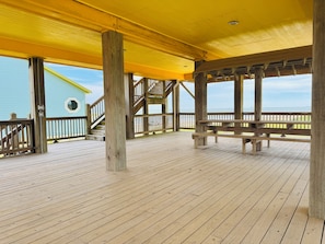 Eine Holzterrasse mit gelbem Dach, Holzwertungen und Blick auf das Meer.