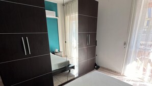 Een slaapkamer met een groot bed, een kledingkast, een spiegel en uitzicht op het omliggende landschap.