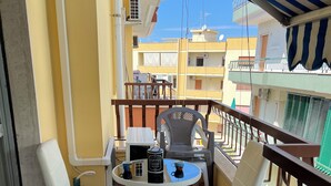 Een balkon met twee witte stoelen, een kleine tafel en een koffieapparaat.