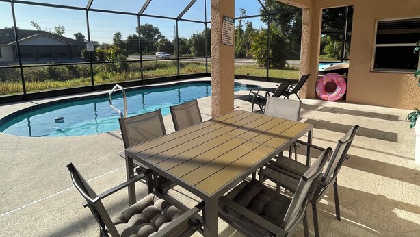 Área externa com piscina, mesa, cadeiras, ventilador de teto e vista da paisagem ao redor.
