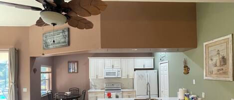 A modern kitchen with white cabinets, a central island, and a ceiling fan.
