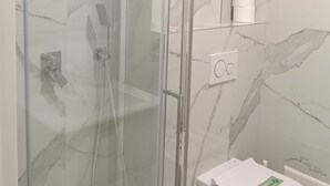 Ein modernes Badezimmer mit einer Duschkabine, einer Toilette und einer Wand mit Marmoroptik.