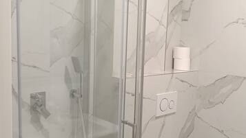 Une salle de bain moderne avec une douche à parois de verre, des toilettes et un mur décoré d’un motif imitant le marbre.