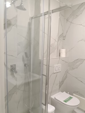 Ein modernes Badezimmer mit einer Duschkabine, einer Toilette und einer Wand mit Marmoroptik.
