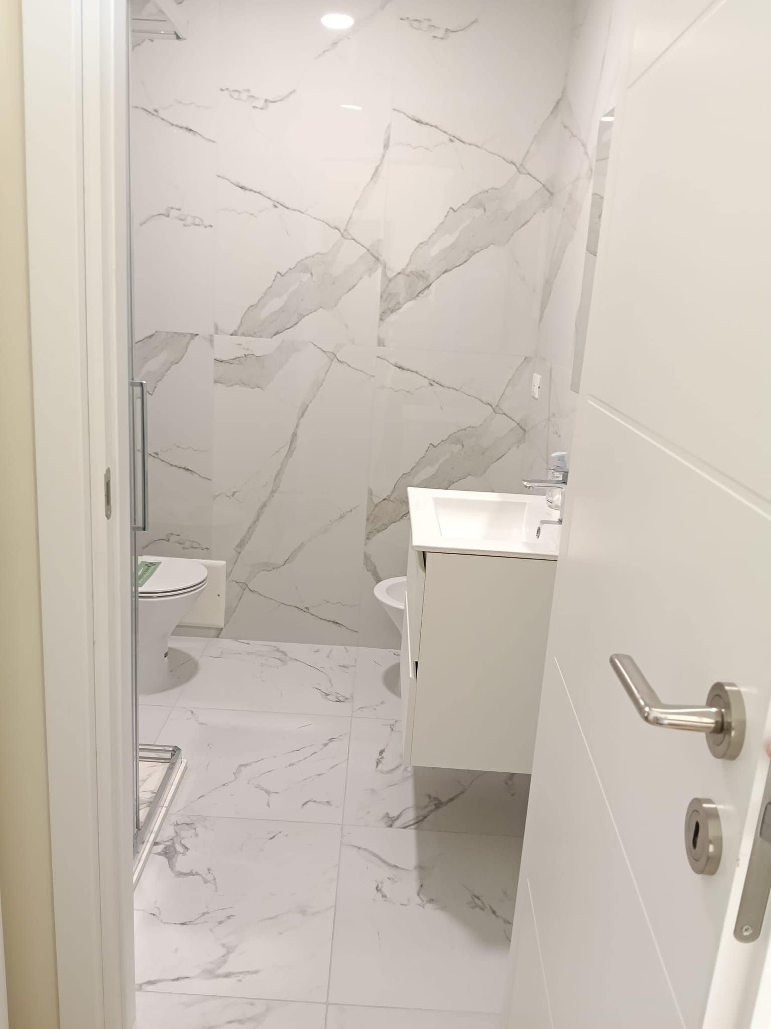 Une salle de bain avec un sol en marbre, des toilettes, un lavabo et un espace douche.