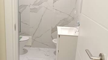 Une salle de bain avec un sol en marbre, des toilettes, un lavabo et un espace douche.