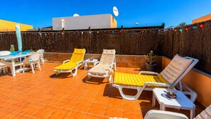 A rooftop terrace with white lounge chairs, a table, and chairs. - Nur house villa & private pool (La Oliva)