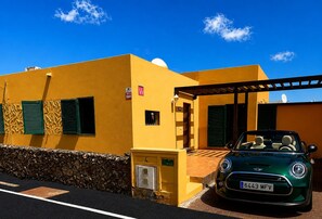 A yellow building with a green convertible parked in front. - Nur house villa & private pool (La Oliva)