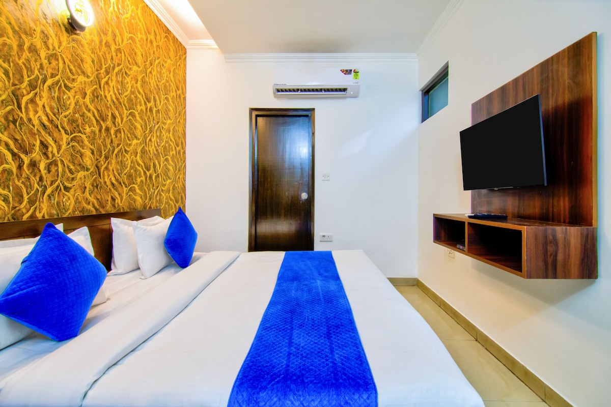 Une chambre d’hôtel avec un lit, une télévision et une étagère fixée au mur.