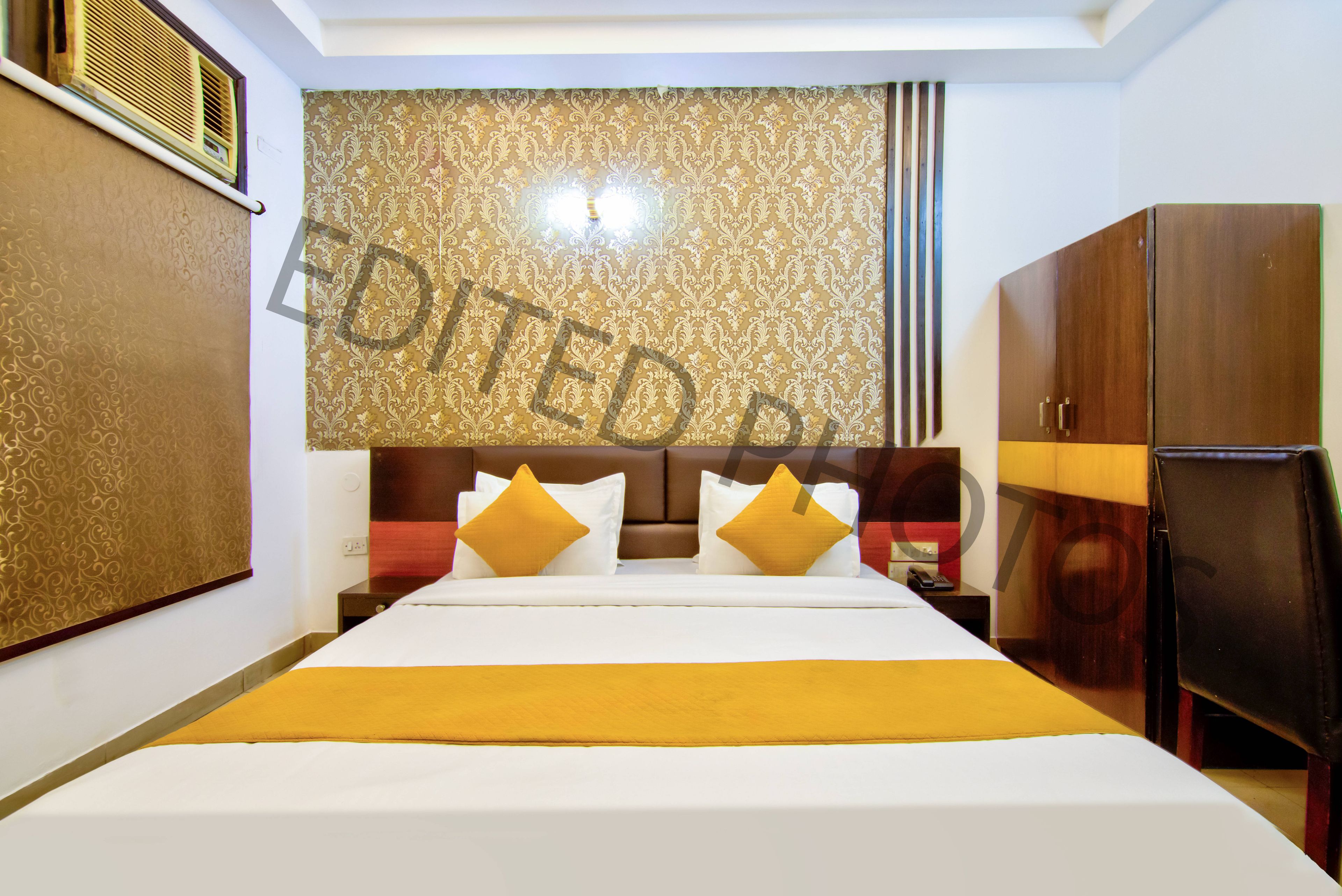 Habitación de hotel con una cama grande, un armario, un escritorio con lámpara y un panel decorativo en la pared.
