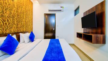 Una habitación de hotel con una cama, televisión y estante en la pared.